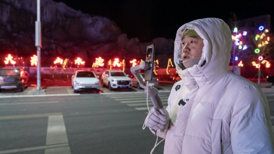 在吉林市阿什哈達霧凇觀景帶,霧凇播報員正在直播。新華社記者 李典 攝